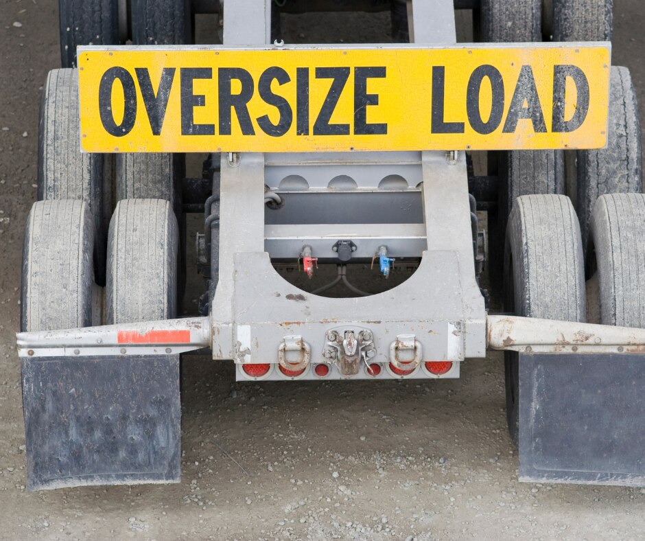 An image of the rear of a truck with a yellow 'Oversize Load' sign on it.